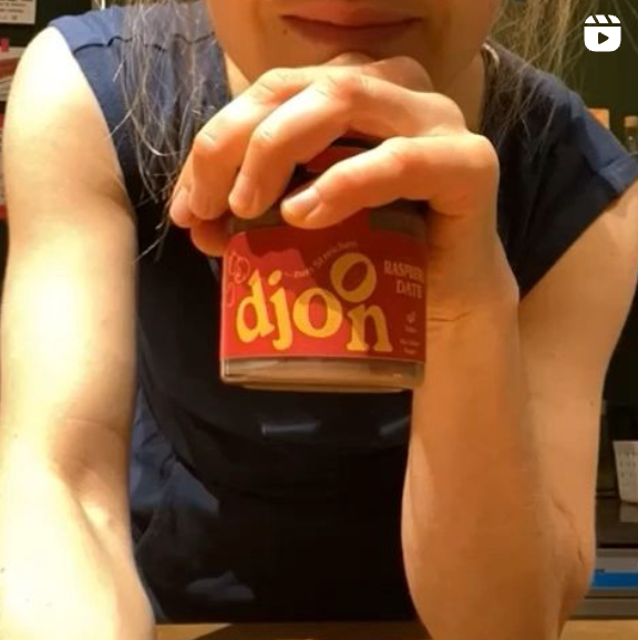 Frau die ein Glas djoon Aufstrich (Sorte Himbeere) zum Frühstück vorbereitet.