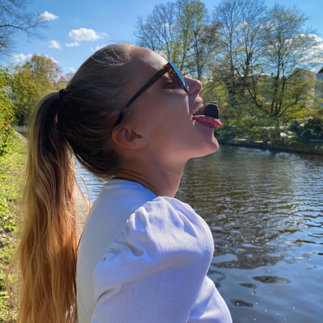 Mädchen mit veganer Praline aus Dattel auf Zunge.