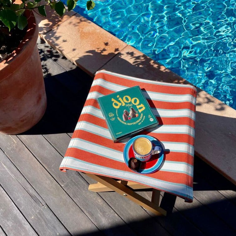 Pralinen Schachtel mit verschiedenen gemischten leckeren Pralinen und einer Tasse Kaffee im Urlaub am Pool.