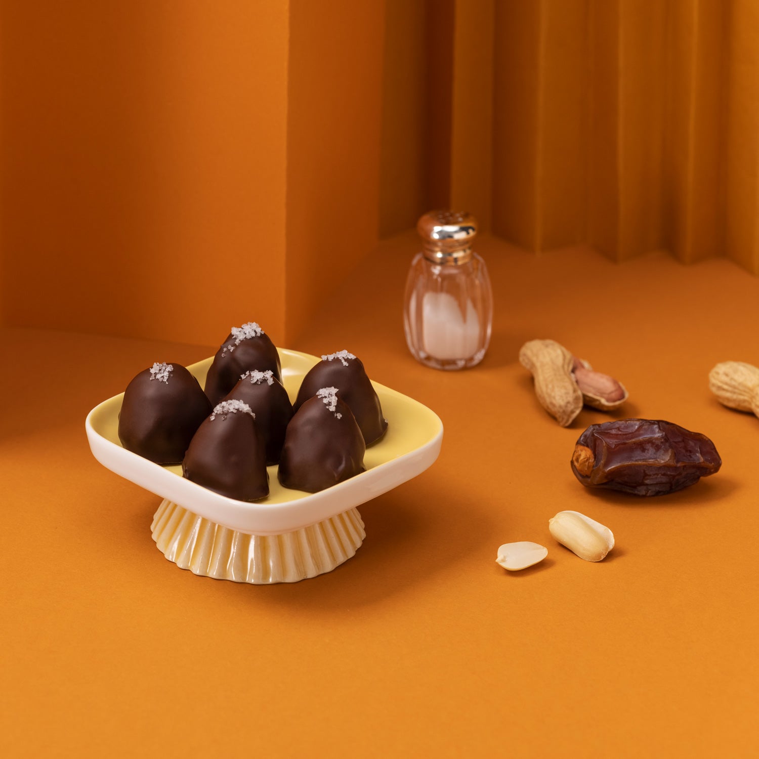 Schale mit mehreren djoon Dattelpralinen neben Erdnüssen, Salz und Medjool Datteln.